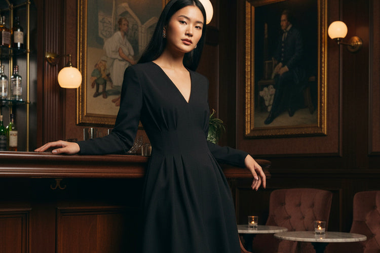 Woman in a black dress standing in an elegant bar setting with vintage decor.